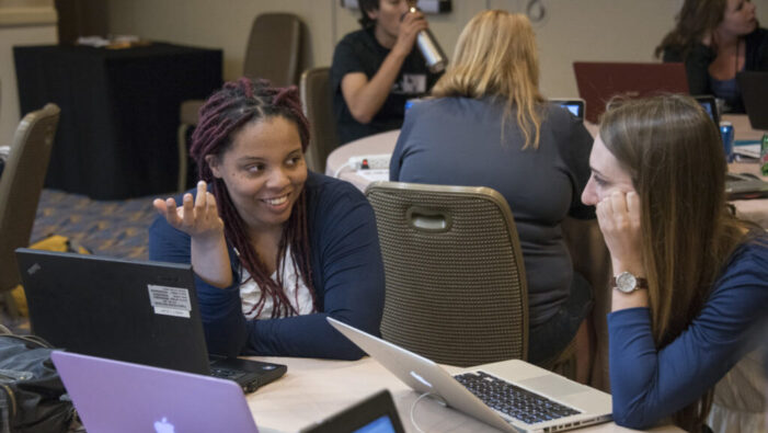 Fellows discussing work together on laptops